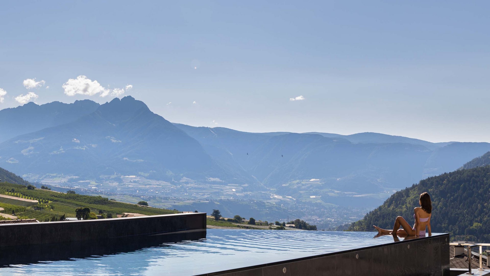 Alpin & Stylehotel Die Sonne: euer Hotel in Partschins Frau entspannt am Infinity-Pool mit Blick auf Berge und Tal